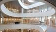 A modern library with multiple levels, glass railings, and extensive book collections.