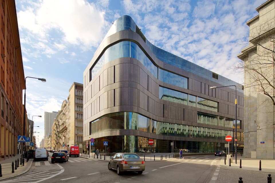 A modern building with a curved facade, a pedestrian crossing, and a 'No Entry' sign.