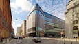 A modern building with a curved facade, a pedestrian crossing, and a 'No Entry' sign.