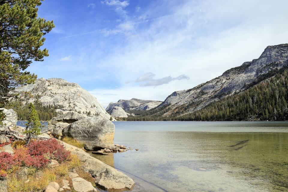 A mountain lake with clear water, surrounded by rocky terrain and trees.
