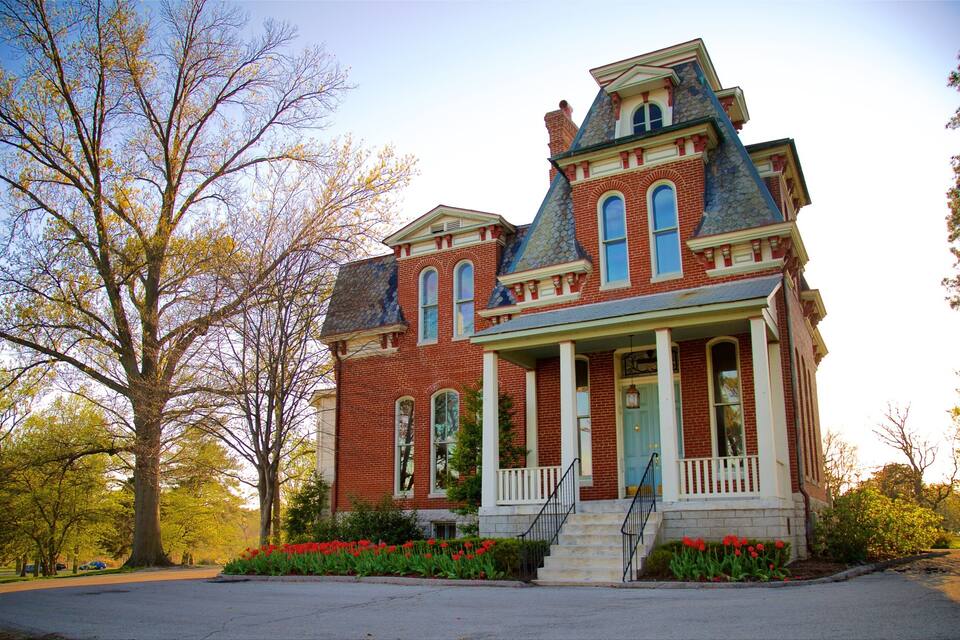 A large, historic brick house with a prominent porch and a blue door.