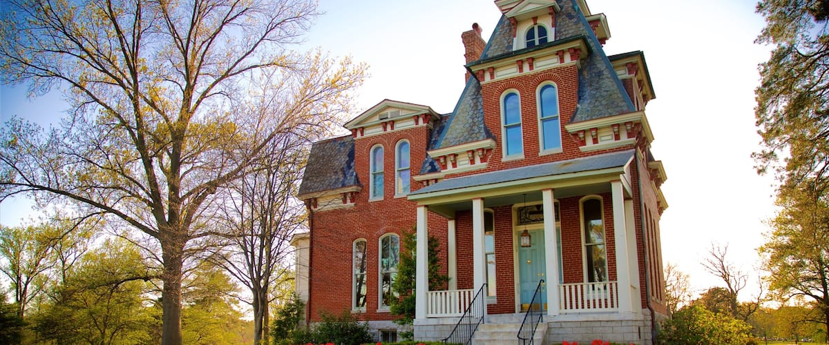A large, historic brick house with a prominent porch and a blue door.