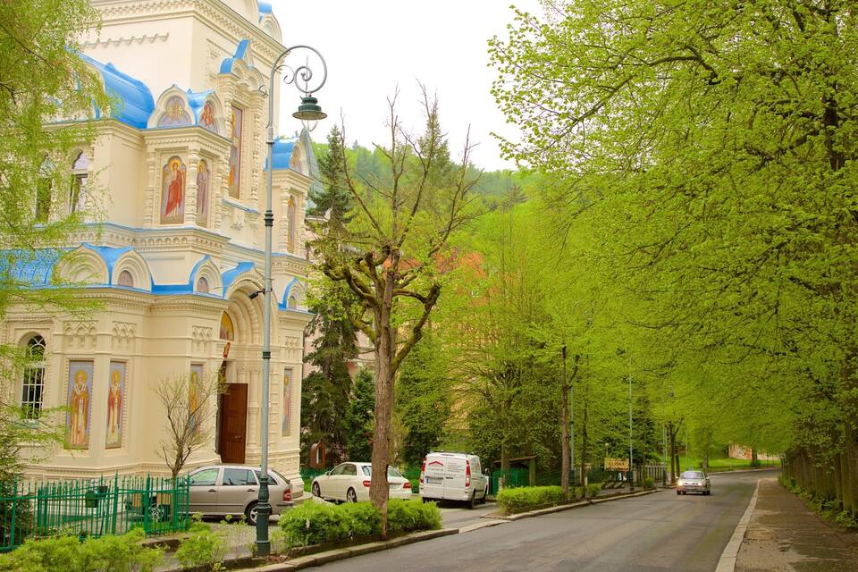 A street lined with trees and a church with blue domes.
