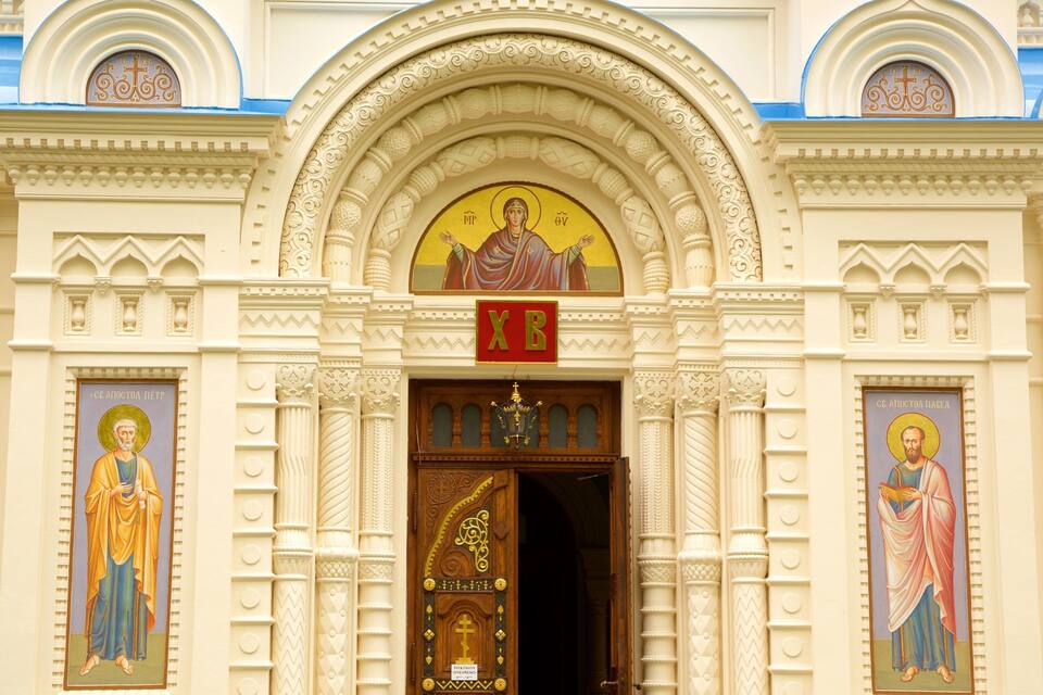 Fachada de igreja com esculturas elaboradas, um arco central e ícones religiosos.
