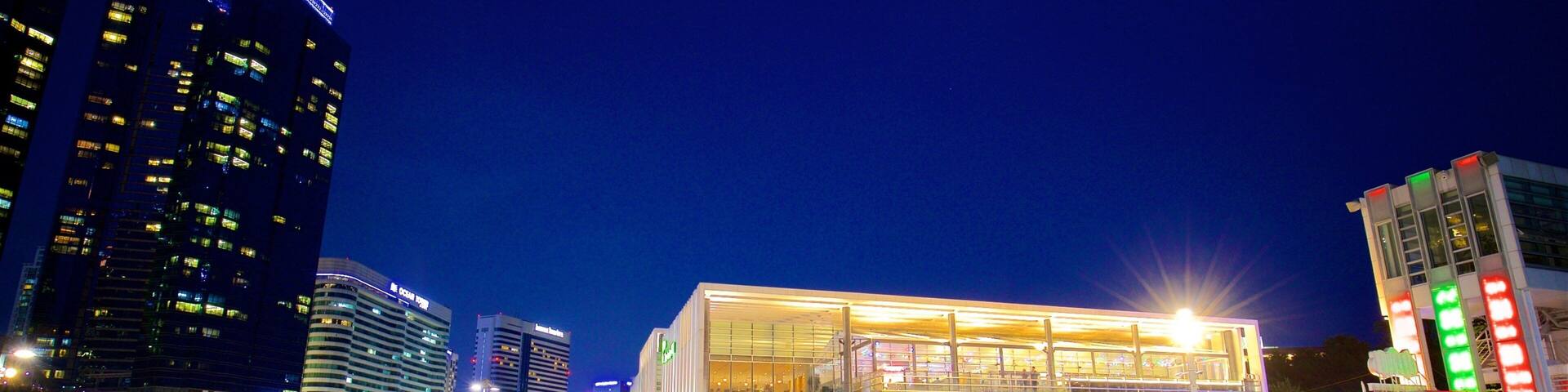 A brightly lit modern building with colorful outdoor seating in a city square at night.