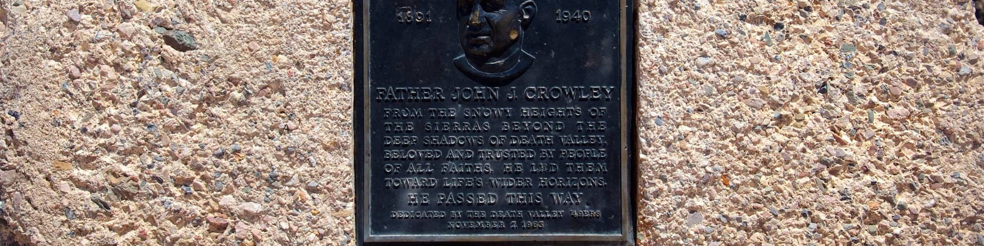 A memorial plaque on a rock with inscriptions and a bust.