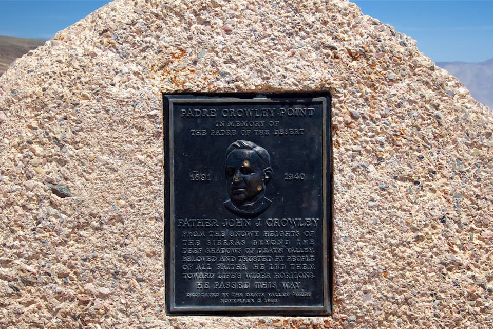 A memorial plaque on a rock with inscriptions and a bust.