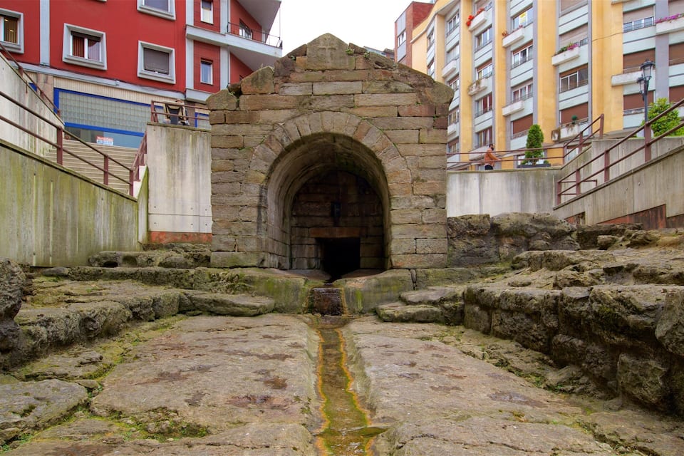 A stone archway leading into a courtyard surrounded by buildings.