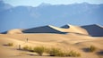 Paisaje desértico con dunas de arena y una persona caminando.