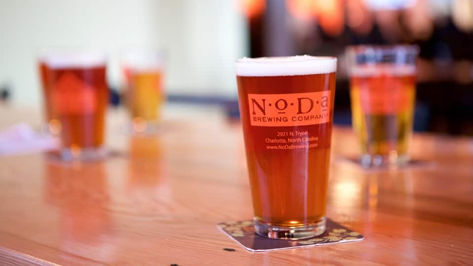 A glass of beer with a label reading "N.O.D. Brewing Company" on a wooden table.