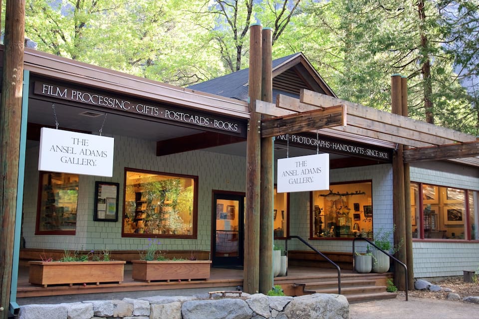 A wooden building with signs for The Ansel Adams Gallery, displaying photographs, books, and postcards.
