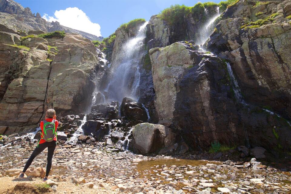 Una cascada se precipita por acantilados rocosos, rodeada de terreno agreste y vegetación escasa.