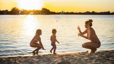 A sunset over a calm body of water with people on the shore.