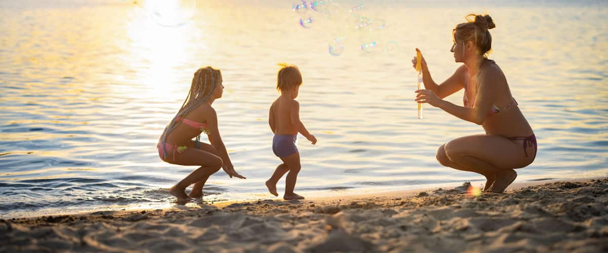 A sunset over a calm body of water with people on the shore.