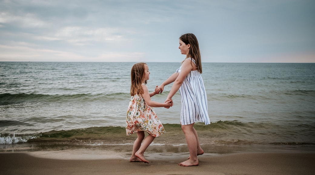 side view of sisters dancing on beach at lake michigan