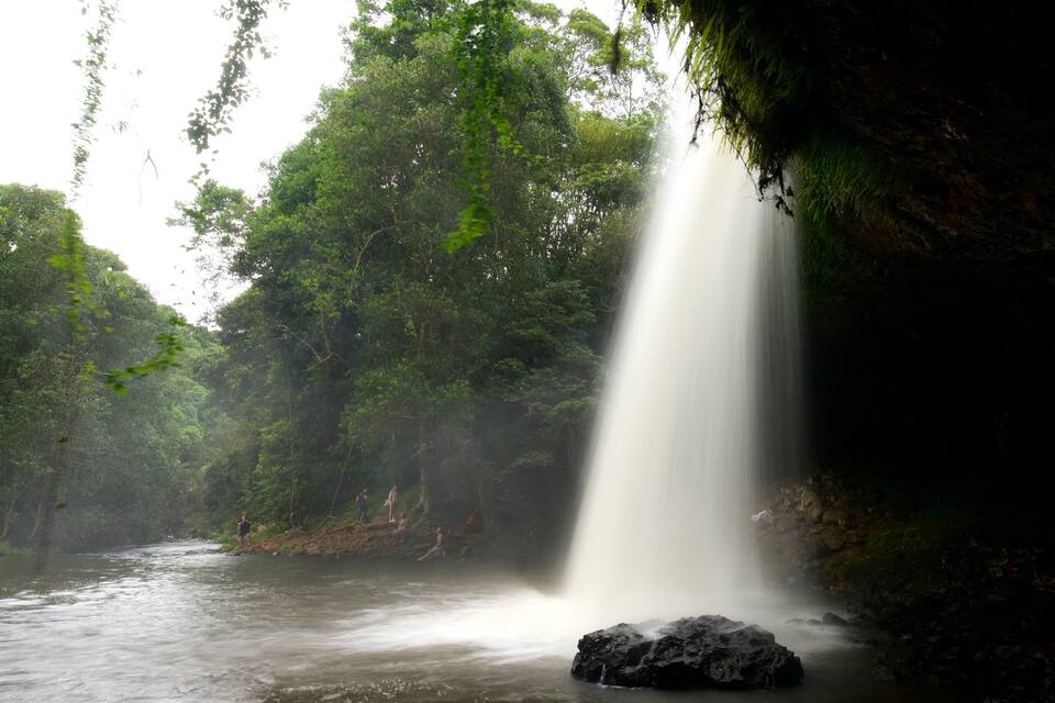 A waterfall in a forested area with a river below.