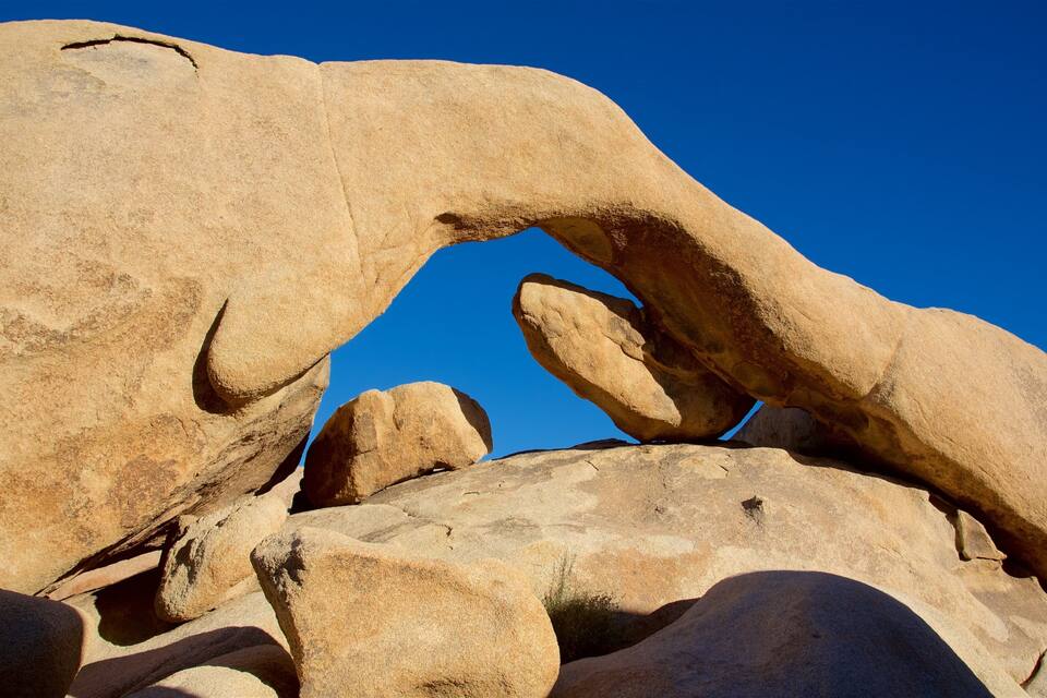 A large rock formation with a natural arch against a clear blue sky.