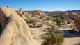A desert landscape with large boulders and sparse vegetation.