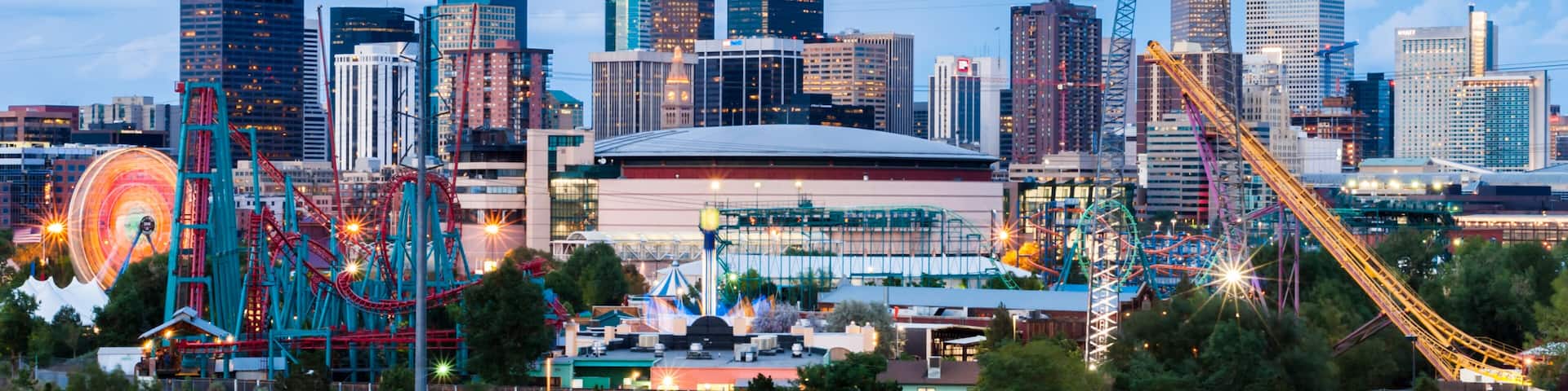A city skyline with a roller coaster, a Ferris wheel, and a stadium.