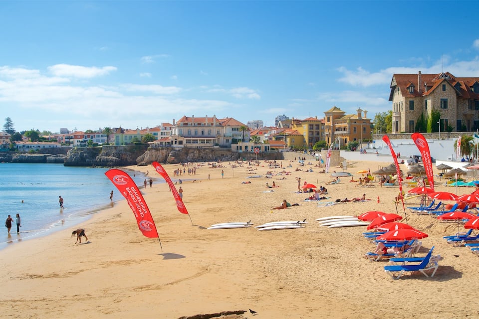 A sunny beach with red flags, people sunbathing, and a building in the background.