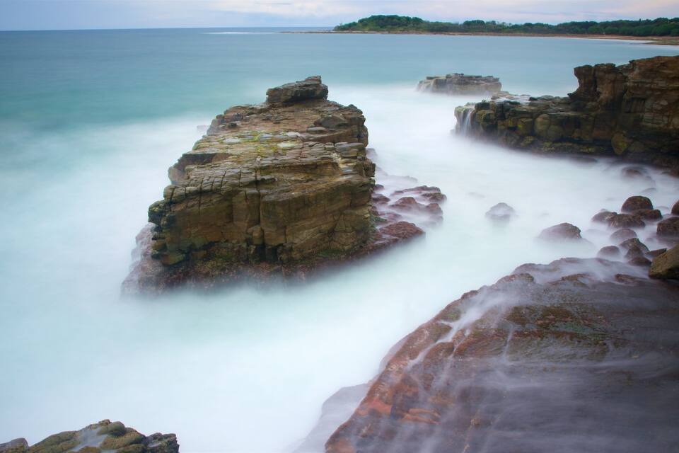 A coastal landscape with prominent rock formations and a calm sea.