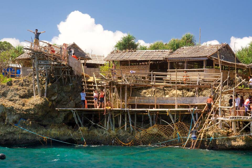 A bamboo structure with multiple levels, overlooking a turquoise sea.