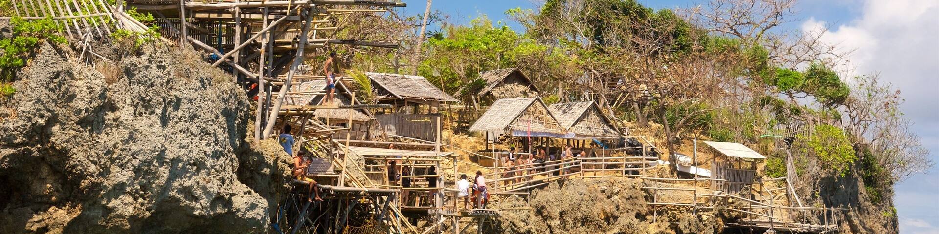 A coastal village with traditional thatched-roof houses built on a rocky cliff.