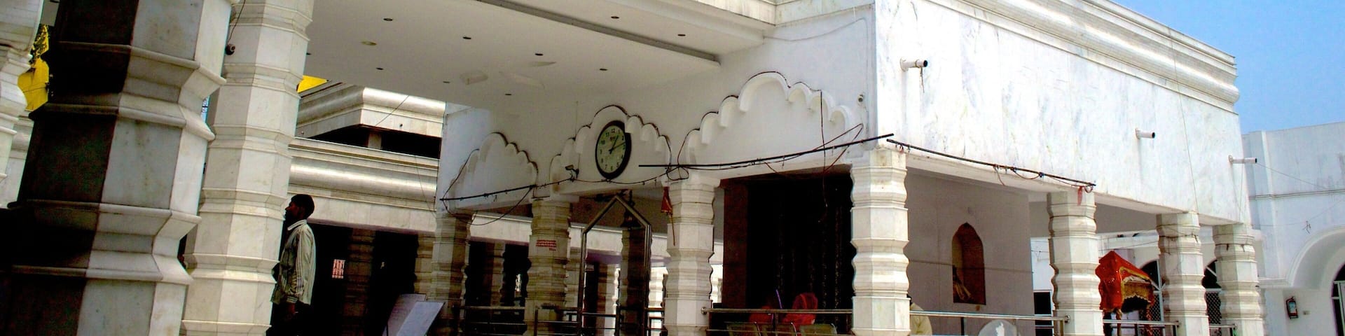 Un bâtiment blanc avec une tour jaune et une horloge sur la façade.