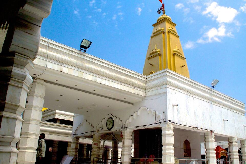 A white building with a yellow tower and a clock on the facade.