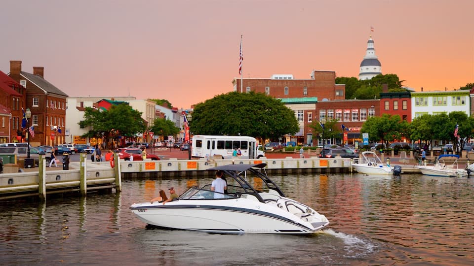 A waterfront with a speedboat, a white bus, and a historic building with a dome in the background.
