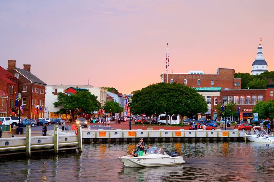 A waterfront cityscape with a prominent clock tower, a marina with boats, and a mix of historic and modern buildings.