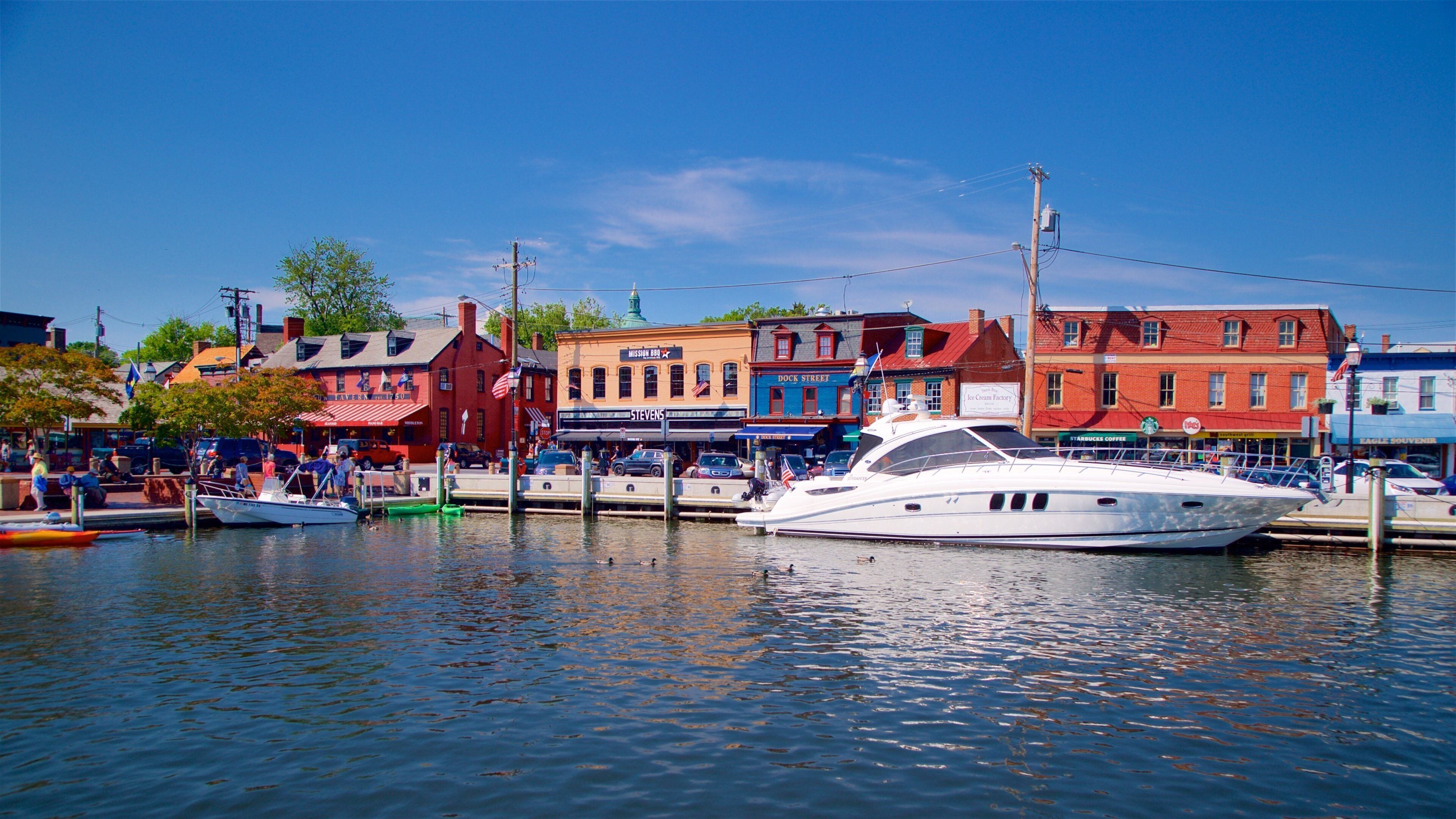 A waterfront with a white yacht docked at the pier, colorful buildings, and a clear blue sky.