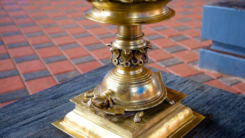 A brass statue with intricate designs on a tiled floor.
