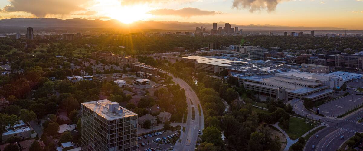 A cityscape at sunset with a prominent building and a curved road.
