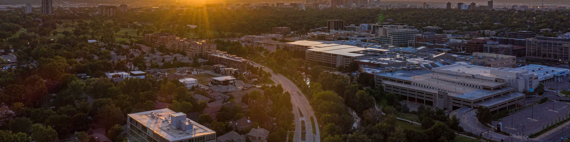 A cityscape at sunset with a prominent building and a curved road.