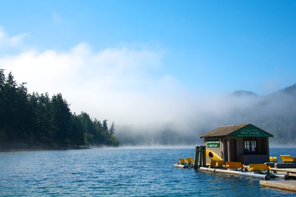 Un point de location de bateaux situé sur un lac paisible, entouré de collines boisées.