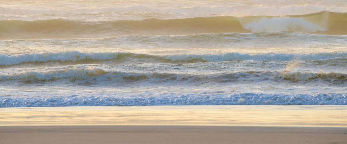 Strahan caracterizando ondas, uma praia de areia e um pôr do sol