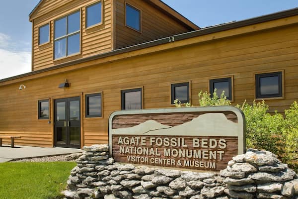 A wooden building with a sign for the Agate Fossil Beds National Monument Visitor Center & Museum.