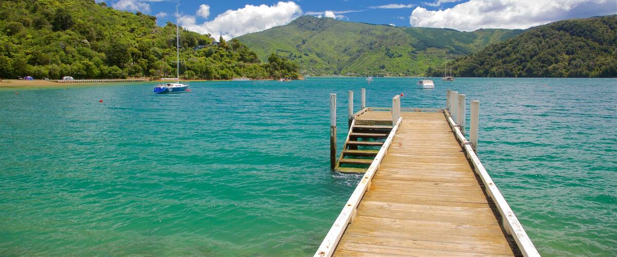 A wooden pier extending into a turquoise lake surrounded by lush green hills.