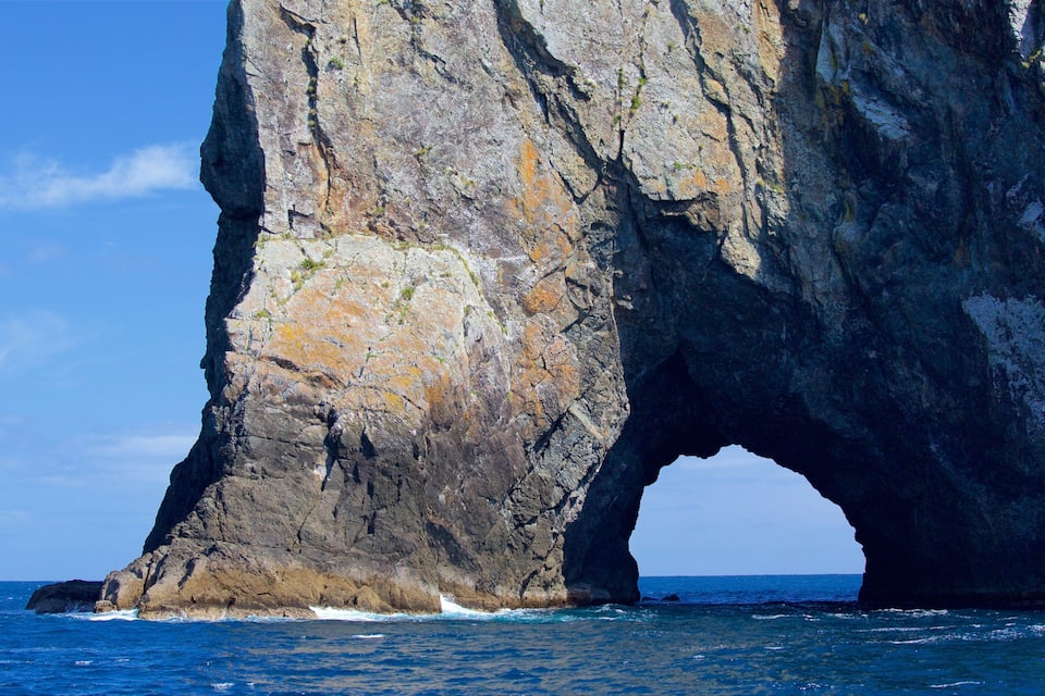 A large rock formation with a natural arch over the ocean.