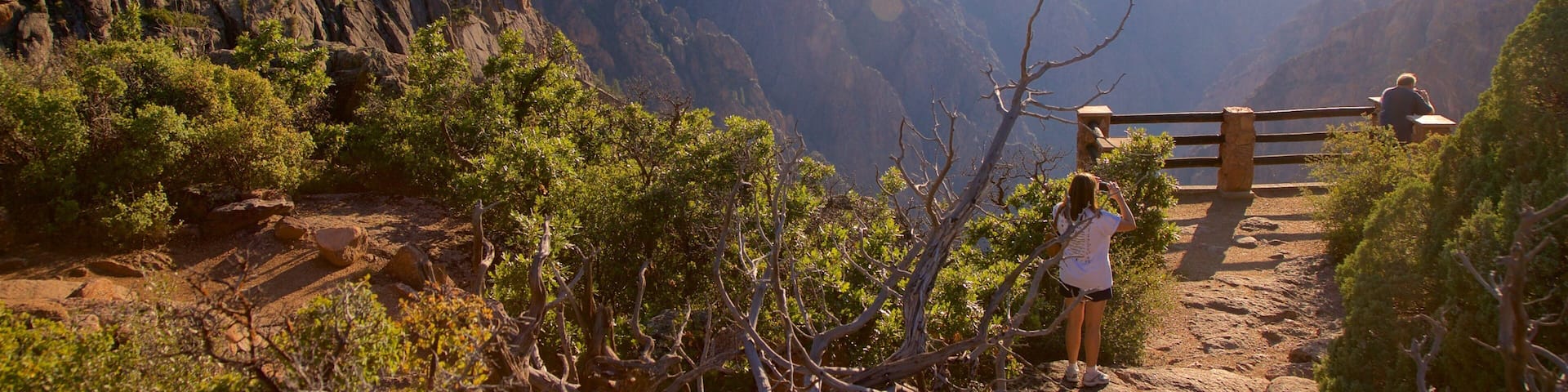 Sendero para excursionistas con terreno rocoso y vegetación escasa, con vistas a un cañón de acantilados escarpados.