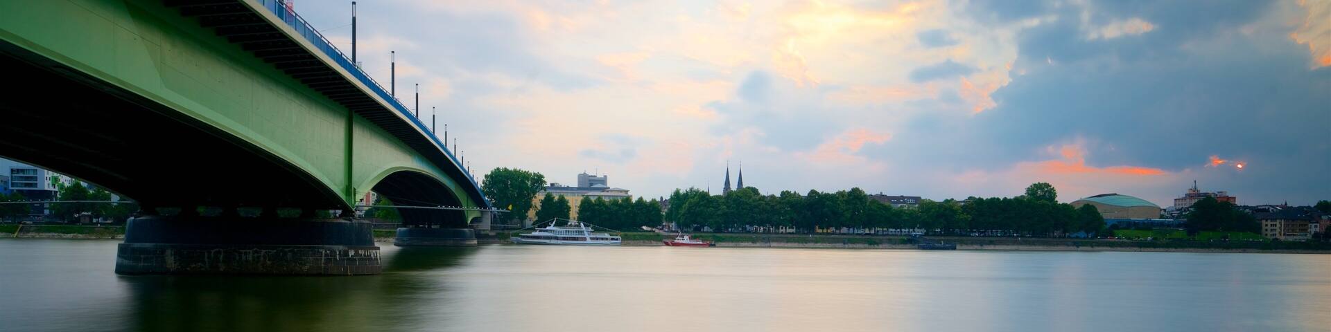 A green bridge over a calm river with a sunset sky.