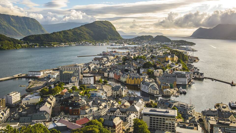 A coastal town with a harbor, surrounded by mountains and a large body of water.