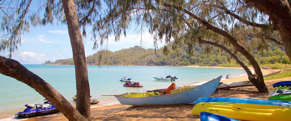 A beach with several boats, including a yellow and a blue one, and a tree-lined shoreline.