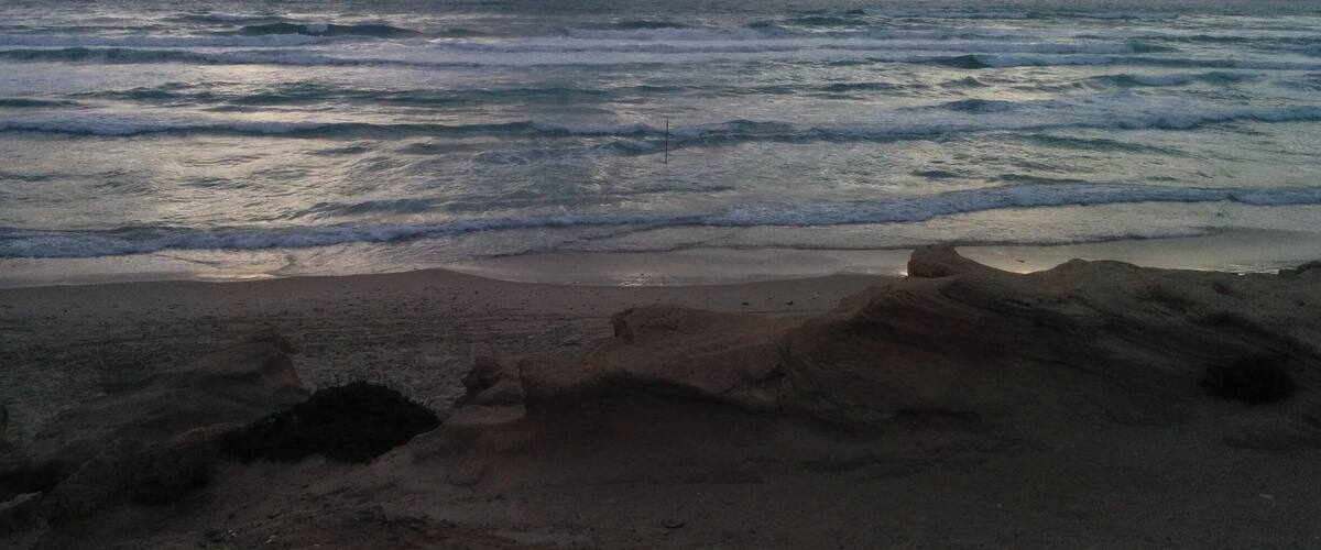 A beach with waves and a cloudy sky.