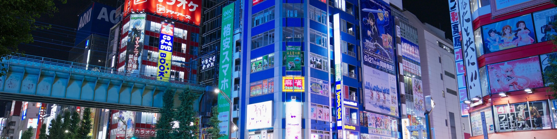 Une rue animée en ville, de nuit, avec des panneaux publicitaires illuminés et un panneau indiquant la limite de vitesse.