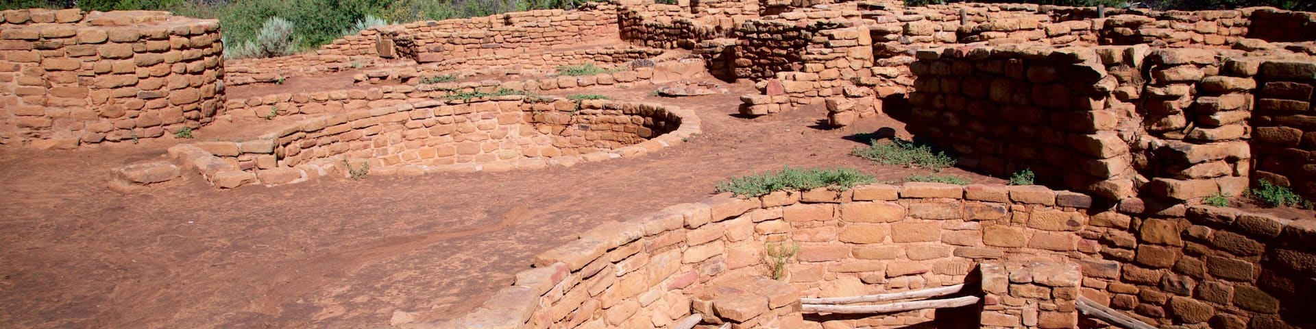 Antiguas ruinas de adobe con estructuras de madera y un cielo azul despejado.