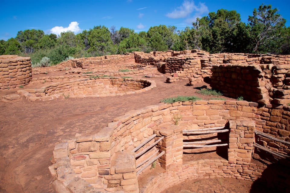 Ancient adobe ruins with wooden structures and a clear blue sky.
