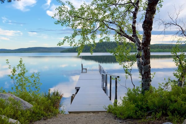 A wooden dock extending into a calm lake surrounded by trees and hills.
