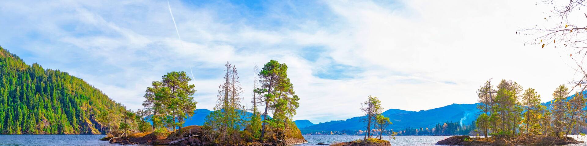A calm lake surrounded by dense forests and mountains.